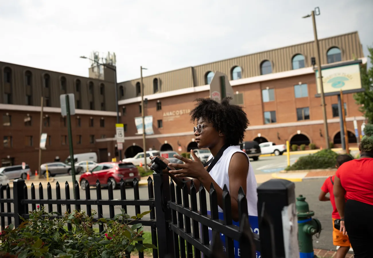 A student practicing photography outside Anacostia High School during Crowns programming.